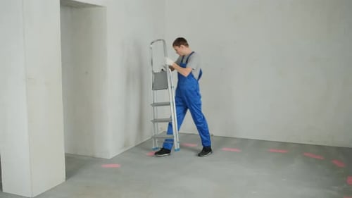 Man Carrying Stepladder Inside Unfinished Room