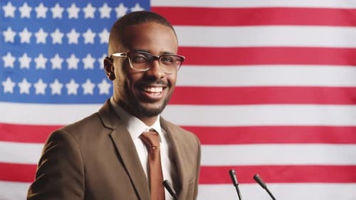 Cheerful Afro-American Politician Posing against U.S. Flag