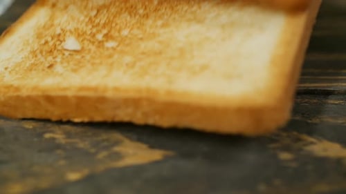 Toasted Bread being placed on a Wood Surface