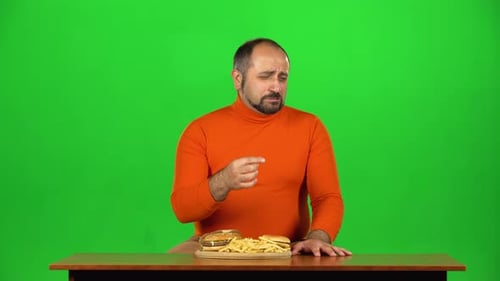 Caucasian Man Stuffs a Lot of Fries in His Mouth, Expressing Disgust, Green Screen