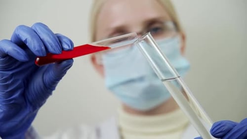 Medical Professional Pouring Liquids Between Test Tubes