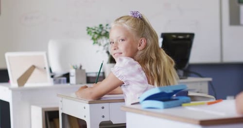 Girl Smiling and Writing at School Desk