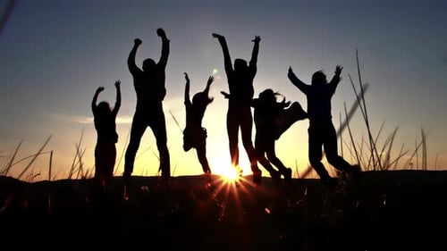 Silhouette von Gruppenfreunden, die zusammen auf den Hügel springen und die Hände zum Himmel heben