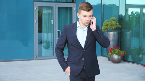 Young Businessman Talking on Phone and Walking in City Street. Handsome Man Commuting To Work and