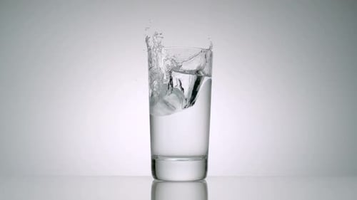 Ice Cube Dropped in Water Creating a Splash