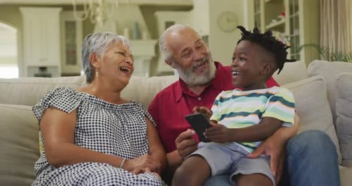 Grandparents Laughing with Grandson Holding Phone