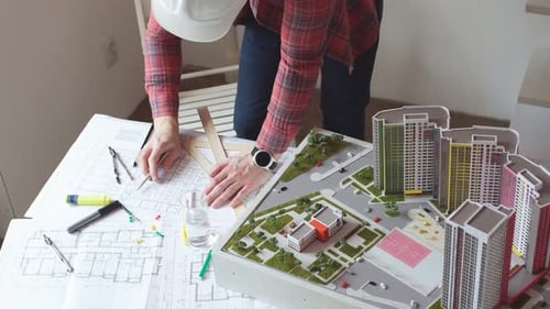 Architects Creating New Project with the Use of Small Model of High-rise Construction.