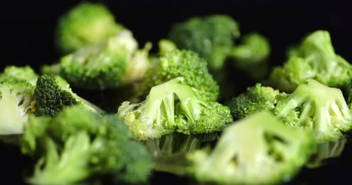 Fresh Green Broccoli Florets Scattered on Black Background