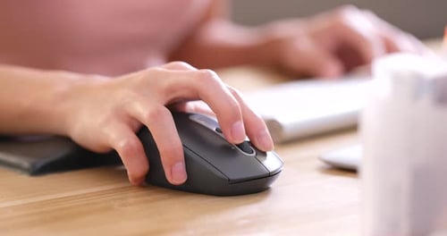 Hands typing on computer keyboard and use of mouse in office