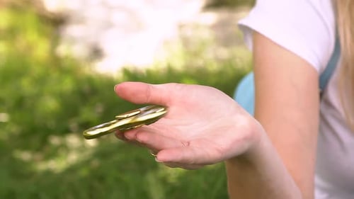 Woman Spinning Gold Fidget Spinner in Her Hand