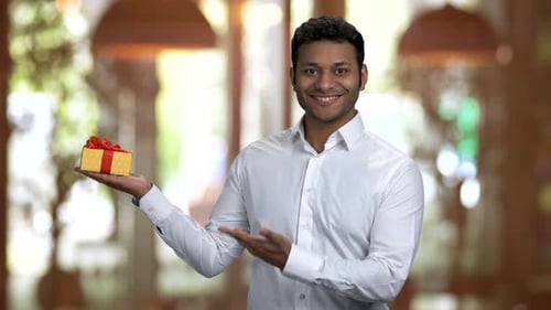 Young Adult Presenting Gift Box with Red Bow