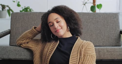 Young Woman Smiling and Leaning Against Couch