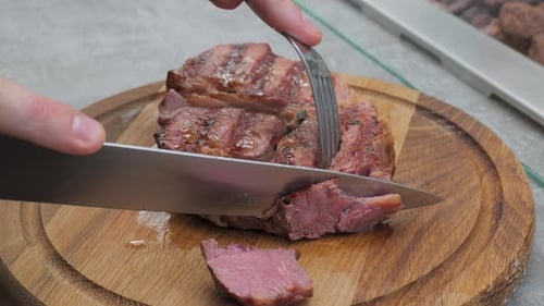 Cutting Grilled Steak on Wooden Board