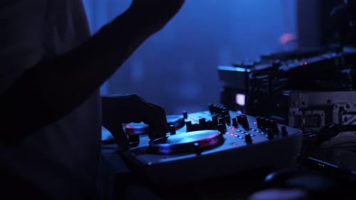 dj playing at the party, close-up hands, colored light