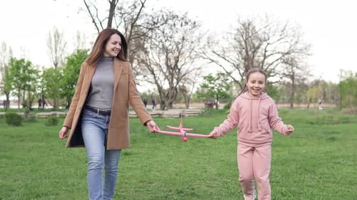 Woman and Child Walk with Toy Airplane in Park