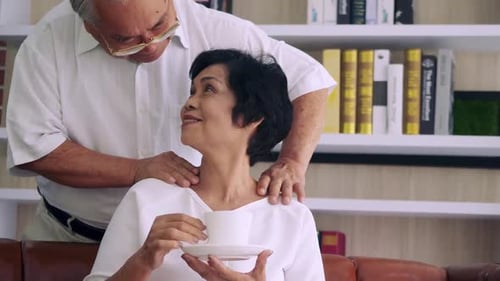 Loving Senior Man Massages Woman Enjoying Tea
