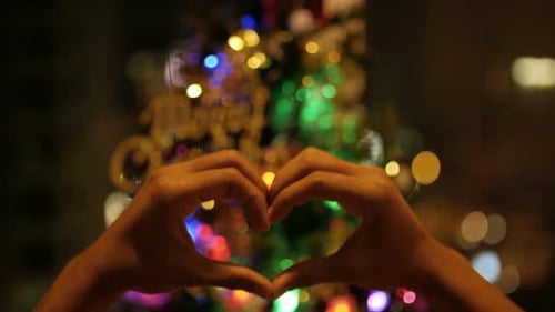 Hands Making Heart Shape with Christmas Tree Lights