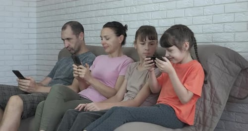 Family Stares at Smartphones on Couch Together