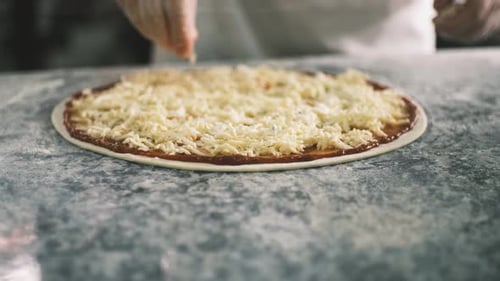 Primer plano para las manos del cocinero poniendo queso en la pizza Cuatro quesos