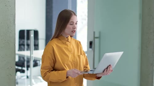 Young Professional Woman Office Manager Video Chatting with Partners Online Carrying Laptop at