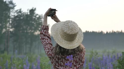 Happy Lady in Straw Hat Makes Selfie in Lupin Flowers Field