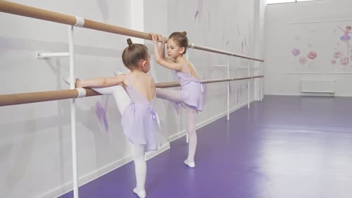 Two Cute Little Ballerinas Stretching at Ballet School Together
