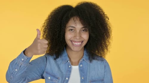 Young Woman Gives Thumbs Up on Yellow Background