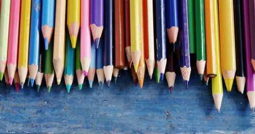 Collection of colorful pencils on a weathered blue board
