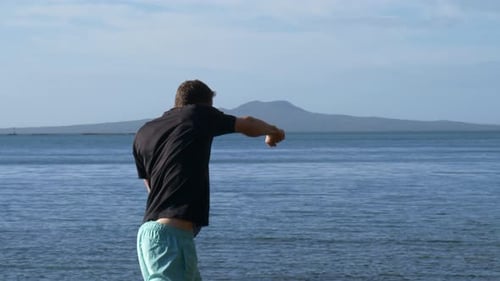 Young man air boxing for fitness at the beach in slow motion