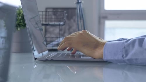Close-up of hands of unrecognizable business person typing on laptop keyboard at the desk