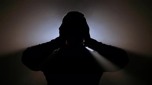 Silhouetted Man in Distress Against Bright Light