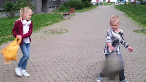 Back to School Children Playing on Street Blonde Boy and Girl Spinning with Backpacks