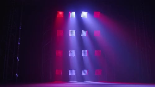 Die Bühne eines kleinen Theaters mit roten und blauen Scheinwerfern. Lichter werden aus der Dunkelheit eingeschaltet.
