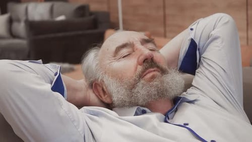 Senior Man Relaxing on Couch with Hands Behind Head