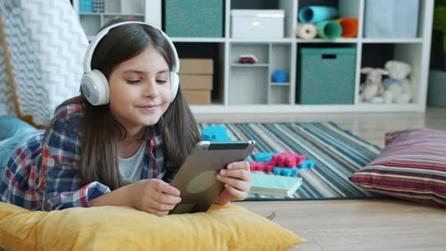 Girl Lies Down Using Tablet with Headphones On