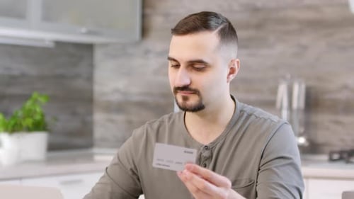 Man Looks at Credit Card at Home