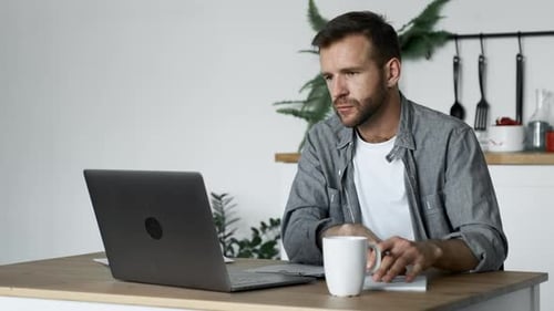 Man Working At Home With Laptop and Notebook