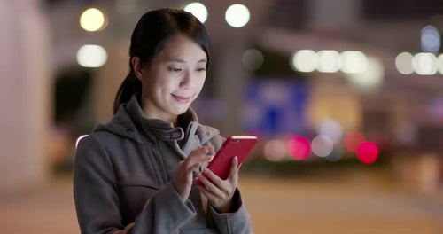 Woman check on smart phone in city at night