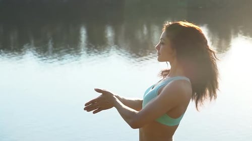 Athletic Woman Exercising in Front of Lake in Sunlight