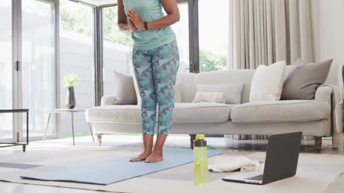 Happy african american wearing sportswear, exercising, using laptop