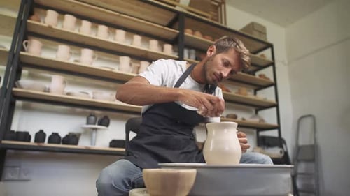 Man Shaping Clay on Pottery Wheel in Studio