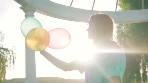 Woman Holding Balloons in a Gazebo