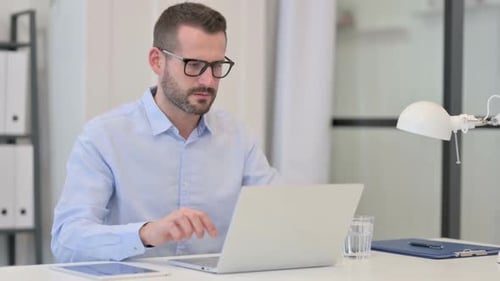 Frustrated Man Working at Computer in Office