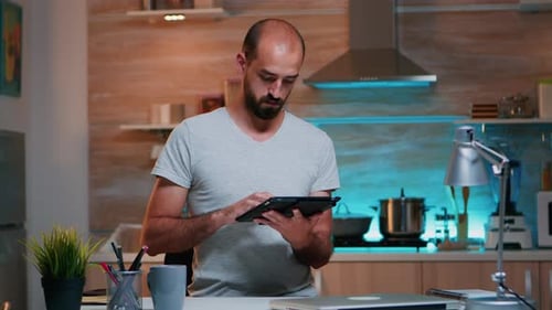 Man Uses Tablet in his Home Kitchen