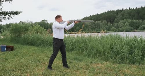 Man Shooting the Gun Outdoors in the Forest Near the River