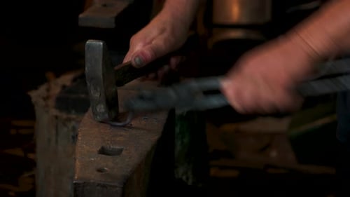 Blacksmith Shaping Metal with Hammer and Tongs