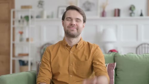 Man Smiling and Waving Hello on Couch
