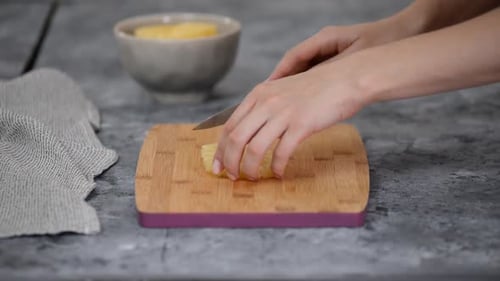 Person Slices Pineapple Ring on Cutting Board