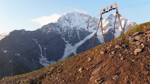 Flying Under the Supports and Cables of an Old Ski Lift Over a Green Mountain Slope Against the