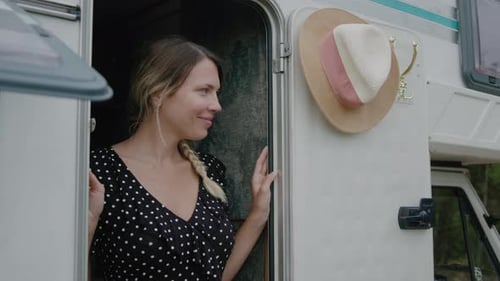 Woman Smiling in Doorway of Camper in Rural Area